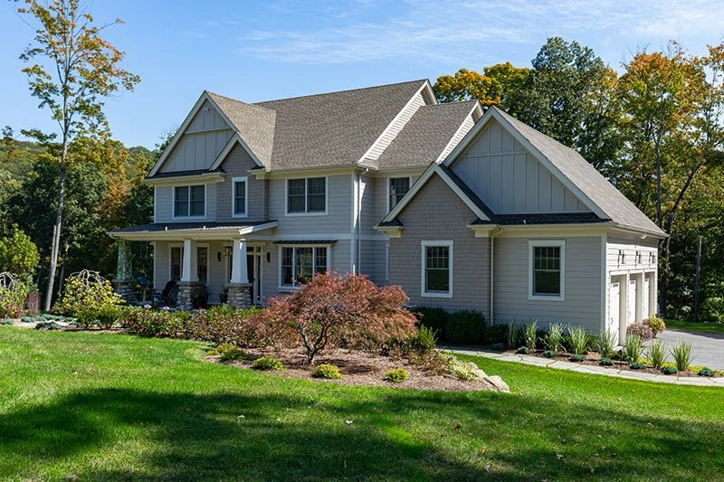 Gray Craftsman house with a covered porch, white trim and landscaped front yard.